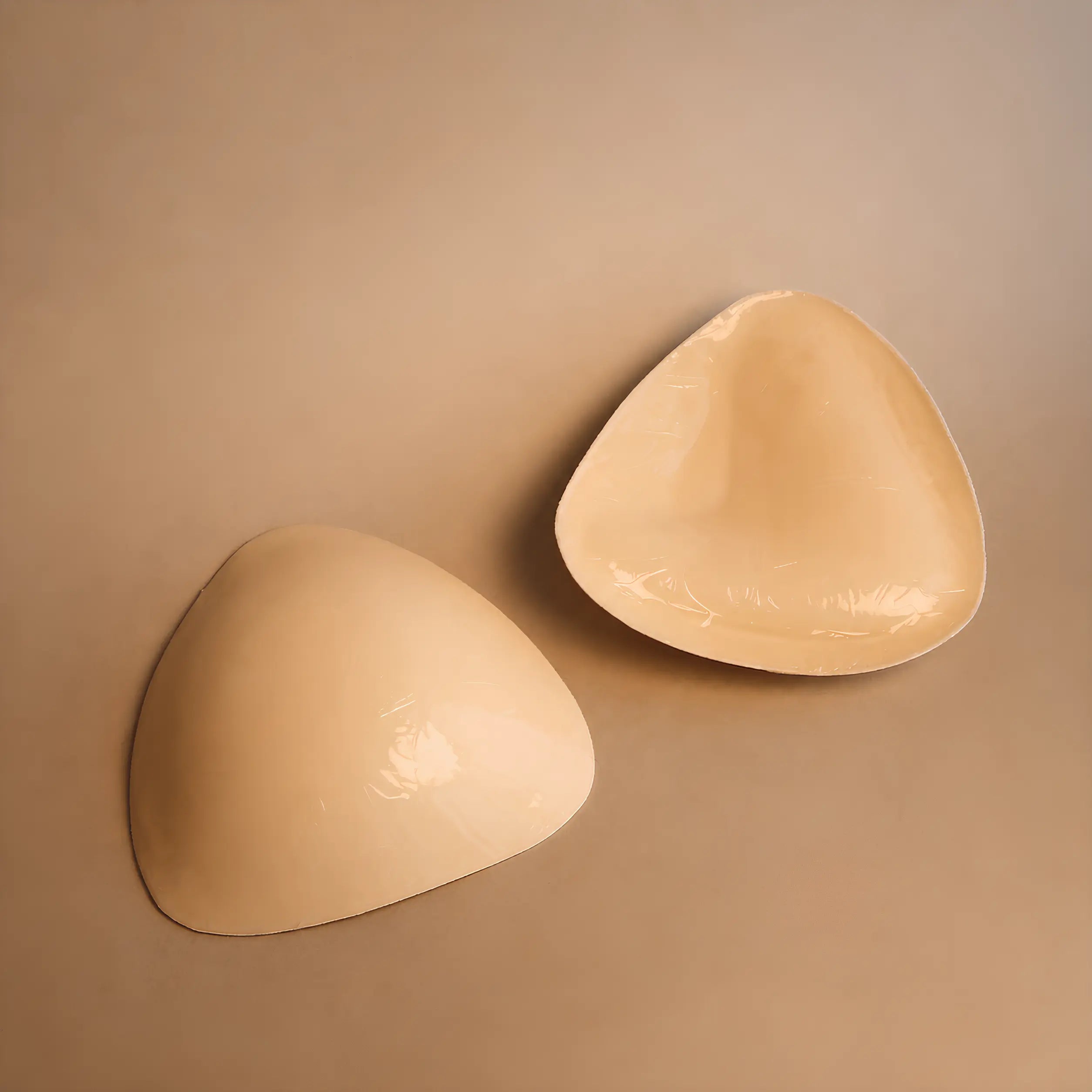 A pair of NIUD Boosters — asymmetric foam pads with a thick anchor edge at the bottom and padding angled outwards.